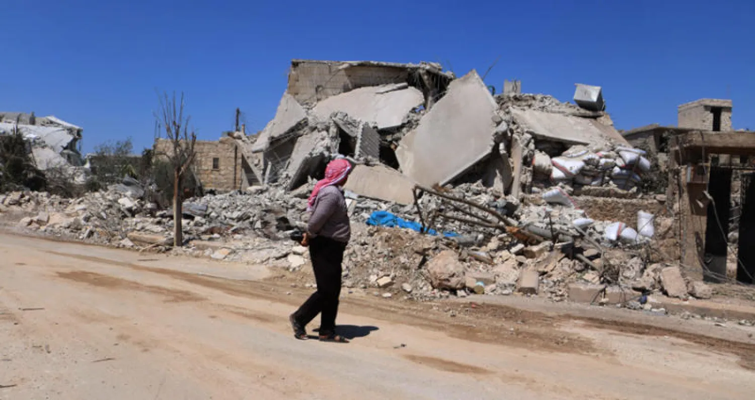 رجل يتفقد ركام أبنية مدمرة بفعل قصف قوات النظام على بلدة أورم الكبرى في ريف حلب الغربي ليلة الجمعة (أ.ف.ب)