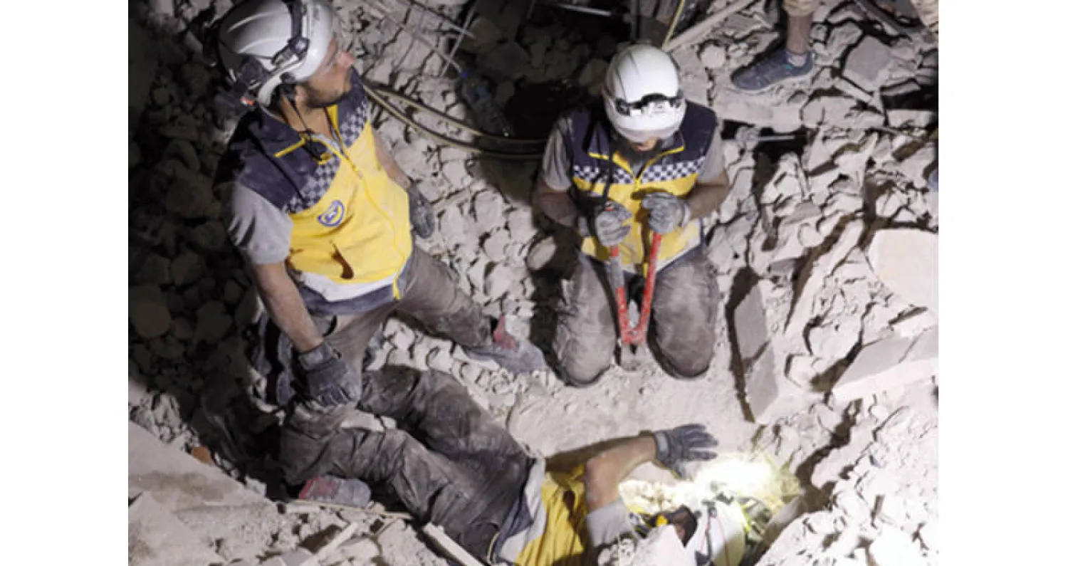 عمّال إنقاذ من جماعة «الخوذ البيضاء» يبحثون عن ضحايا أو ناجين بين الأنقاض في بلدة تعرضت لقصف قوات النظام غرب حلب ليلة الجمعة (أ.ف.ب)