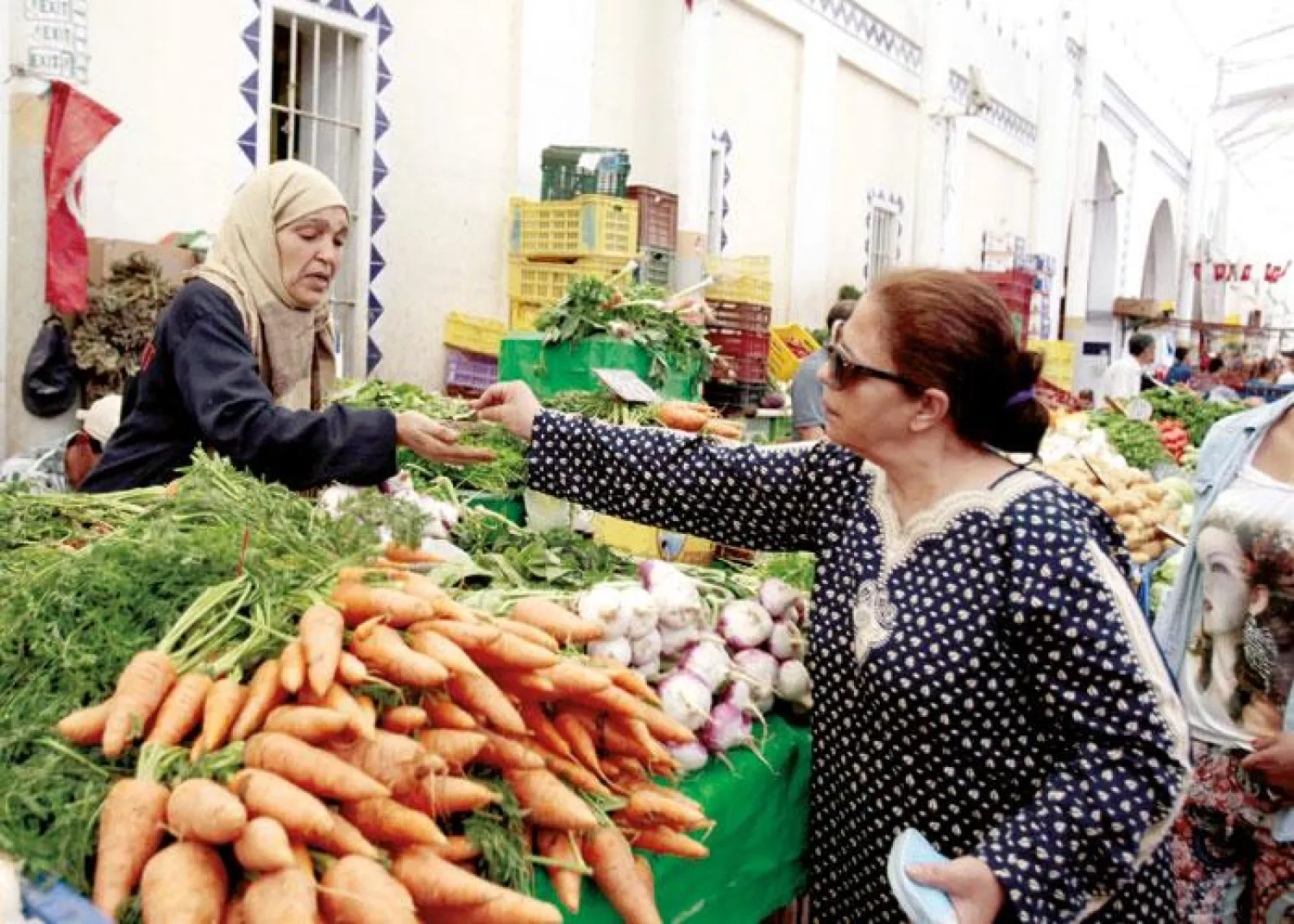 A woman buys vegetables from a vendor at a market in Tunis. (Reuters)