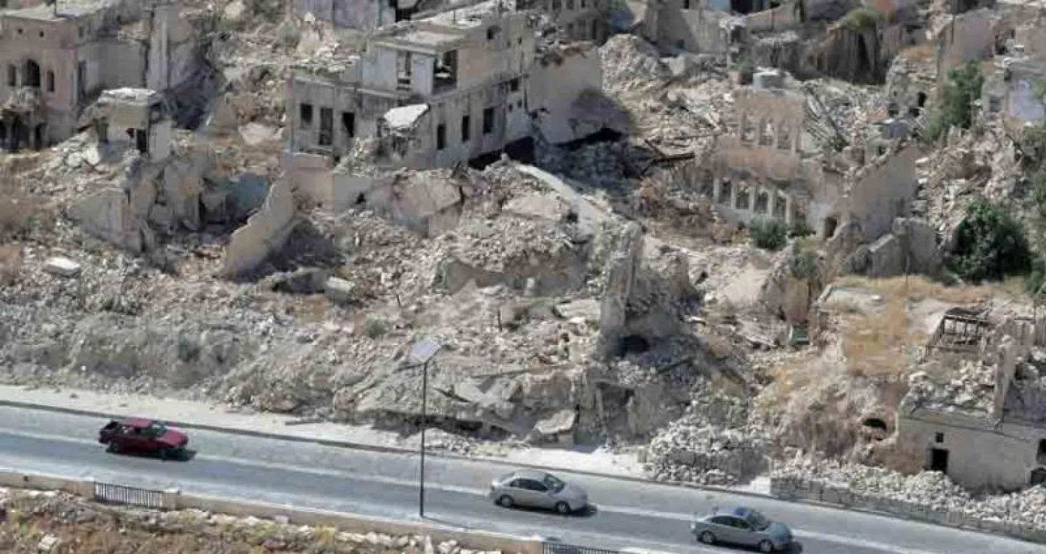 مواطنون يقودون سياراتهم بجانب أبنية مهدمة في مدينة حلب شمال سوريا أول من أمس (أ.ب)