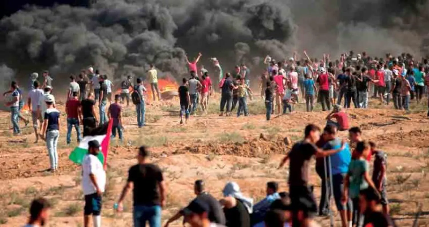 سحب الدخان تتصاعد من اطارات سيارات أحرقها فلسطينيون أمس بالقرب من حدود غزة مع اسرائيل (أ.ف.ب)