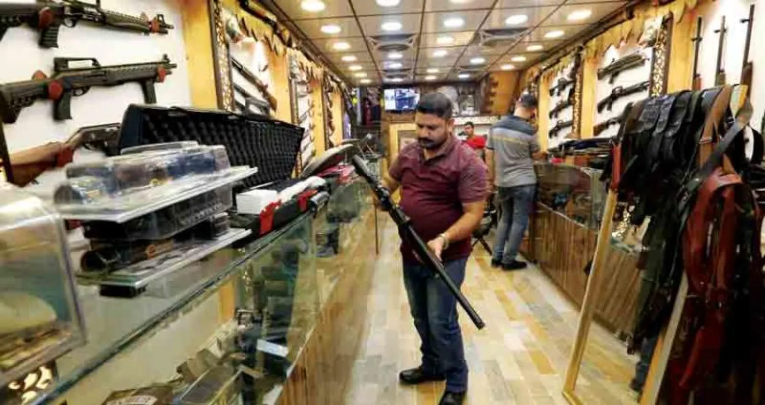 عراقي يفحص بندقية قبل شرائها في متجر للأسلحة في بغداد (رويترز)