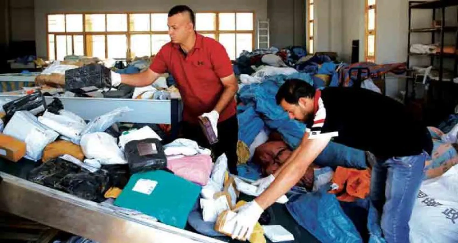 عمال بريد يبحثون في أطنان البضائع والرسائل المحتجزة في مكتب بريد أريحا بالضفة الغربية منذ 8 سنوات (أ.ب)