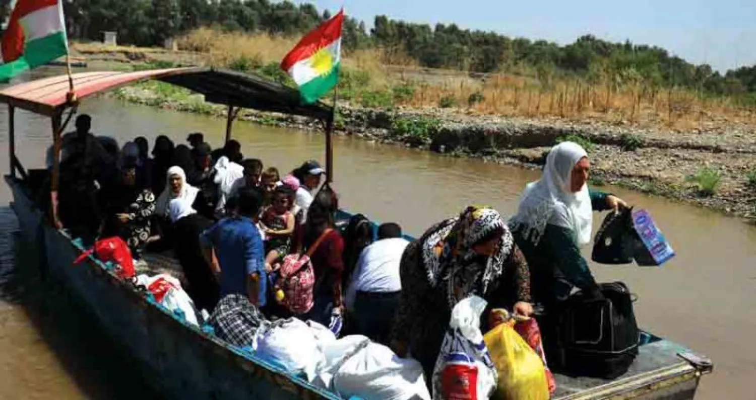 عائلات تعبر من كردستان العراق إلى سوريا في قارب عبر نهر دجلة أمس لزيارة أقاربهم بمناسبة العيد (أ.ف.ب)