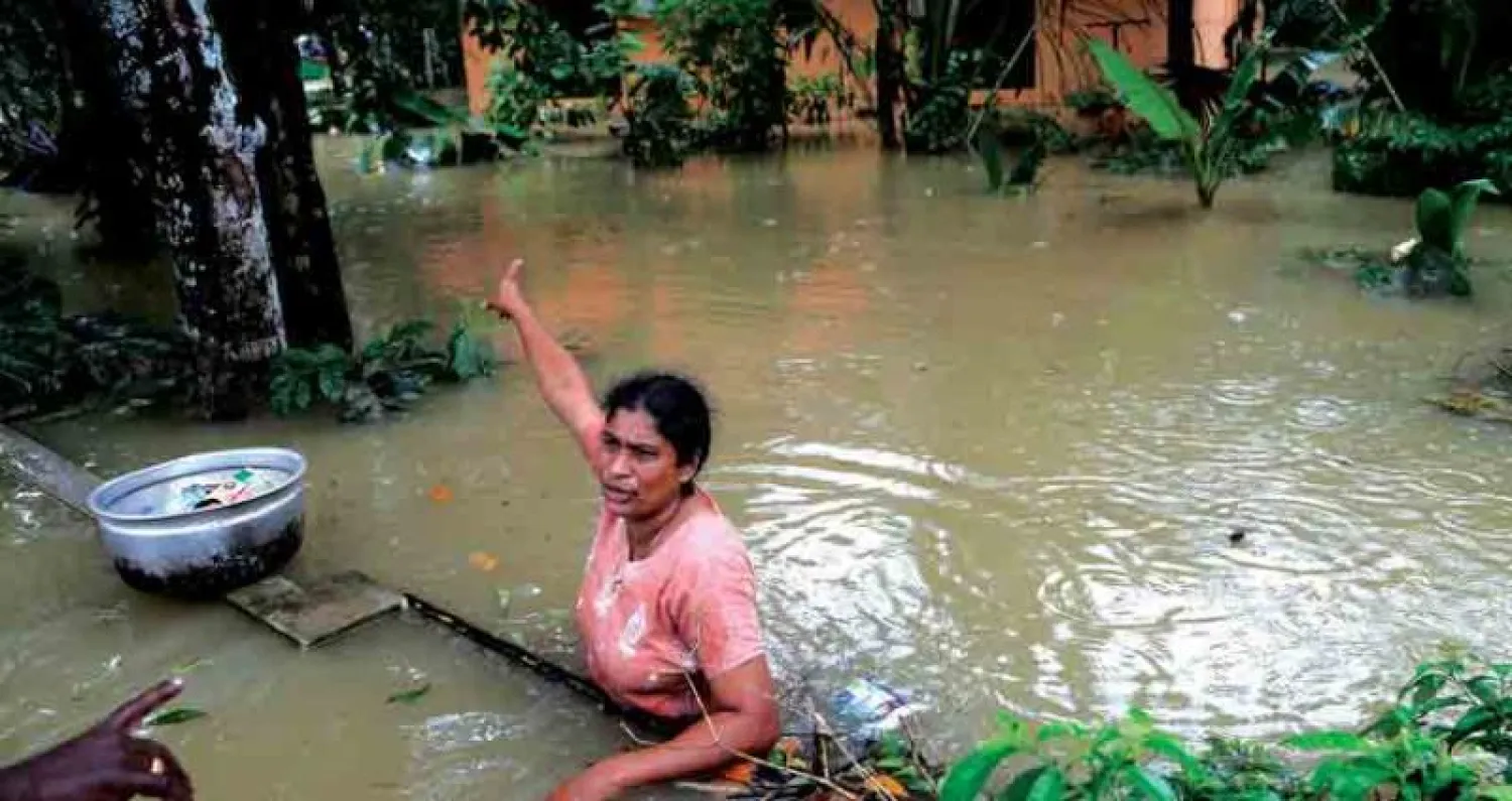 هندية عالقة في الفيضانات تؤشّر إلى بيتها في منطقة شينغانور بكيرالا أمس (أ.ب)