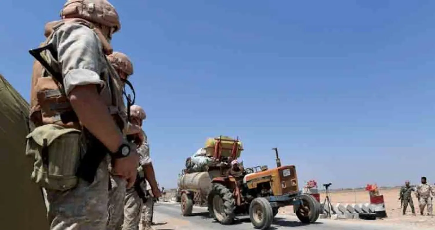 نازحون يمرون أمام عناصر من الشرطة الروسية والنظام السوري في ريف إدلب أمس (أ.ف.ب)