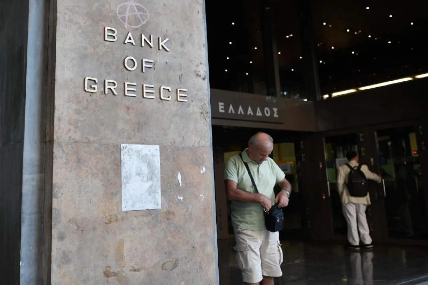 رجل بجوار مقر بنك اليونان في أثينا (أ.ف.ب)