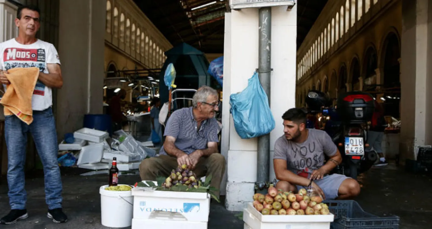 بائعان جائلان يتحدثان في أحد شوارع أثينا مع انتهاء برنامج الإنقاذ (أ.ب)