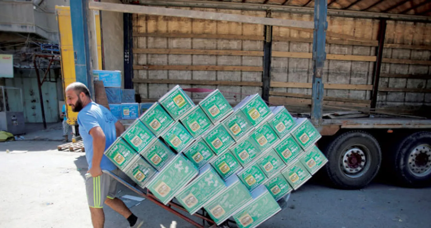 عامل يفرغ حمولة شاحنة من البضائع الإيرانية في بغداد (رويترز)