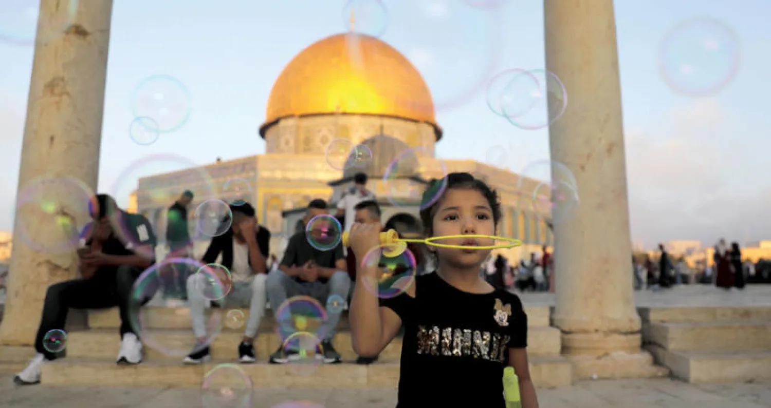 طفلة فلسطينية تطلق فقاعات الصابون في الهواء قرب مسجد قبة الصخرة في القدس ابتهاجاً بالعيد أمس (أ.ف.ب)
