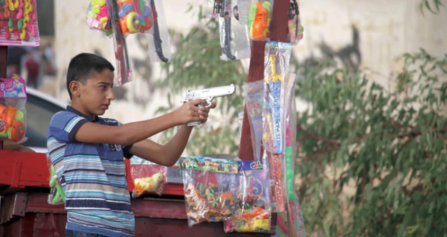 فتى يلعب بمسدس في درعا في أول أيام عيد الأضحى المبارك أمس (أ.ف.ب)