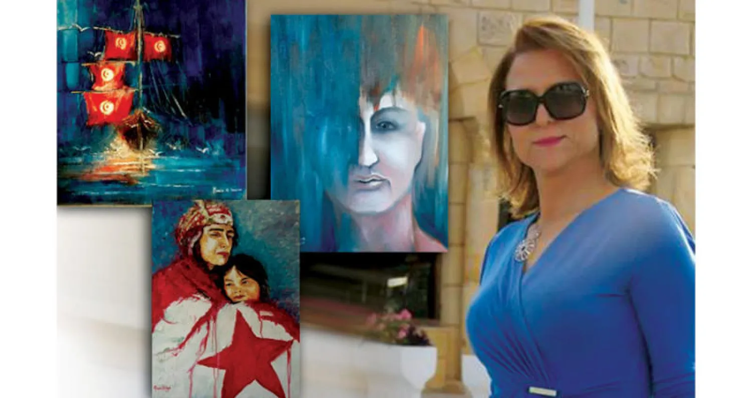 الفنانة التشكيلية التونسية منية الشّاهد إلى جانب لوحاتها