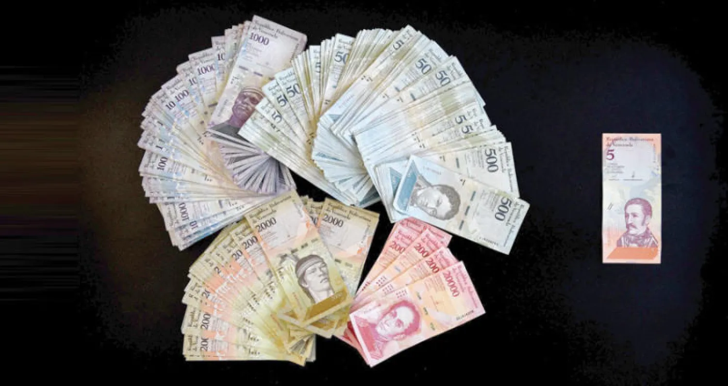 ورقة نقدية فنزويلية من فئة 5 بوليفارات الجديدة وما يوازيها من العملات القديمة (أ.ف.ب)