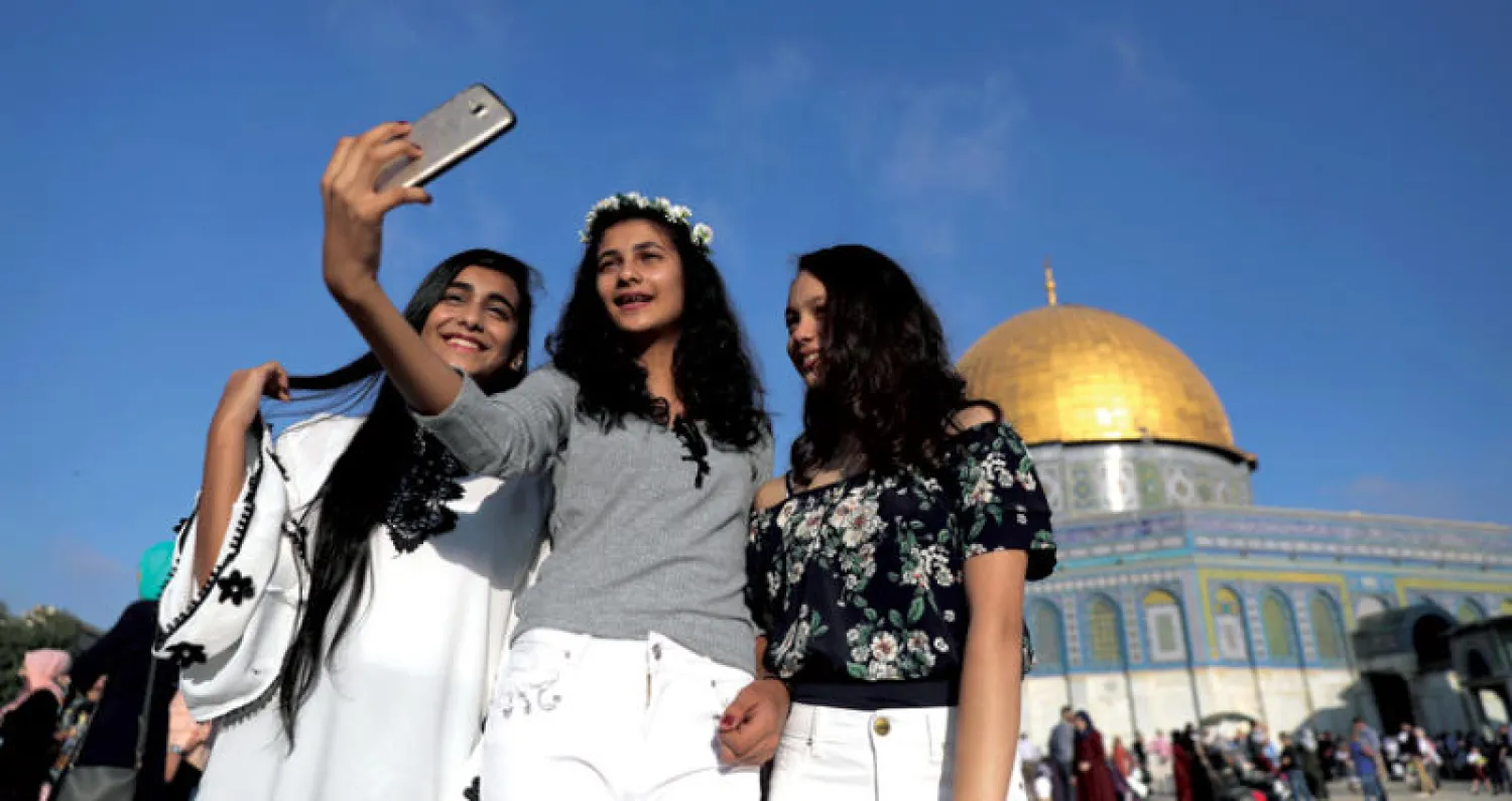 فلسطينيات يلتقطن صورة تذكارية أمام مسجد قبة الصخرة في القدس في أول أيام عيد الأضحى (رويترز)