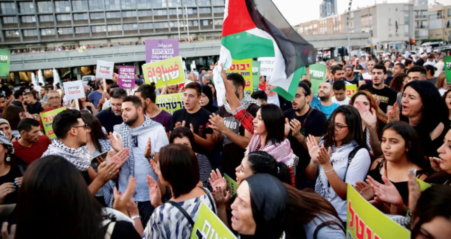 فلسطينيون يرفعون العلم خلال مظاهرة تل أبيب ضد قانون القومية (أ.ب)