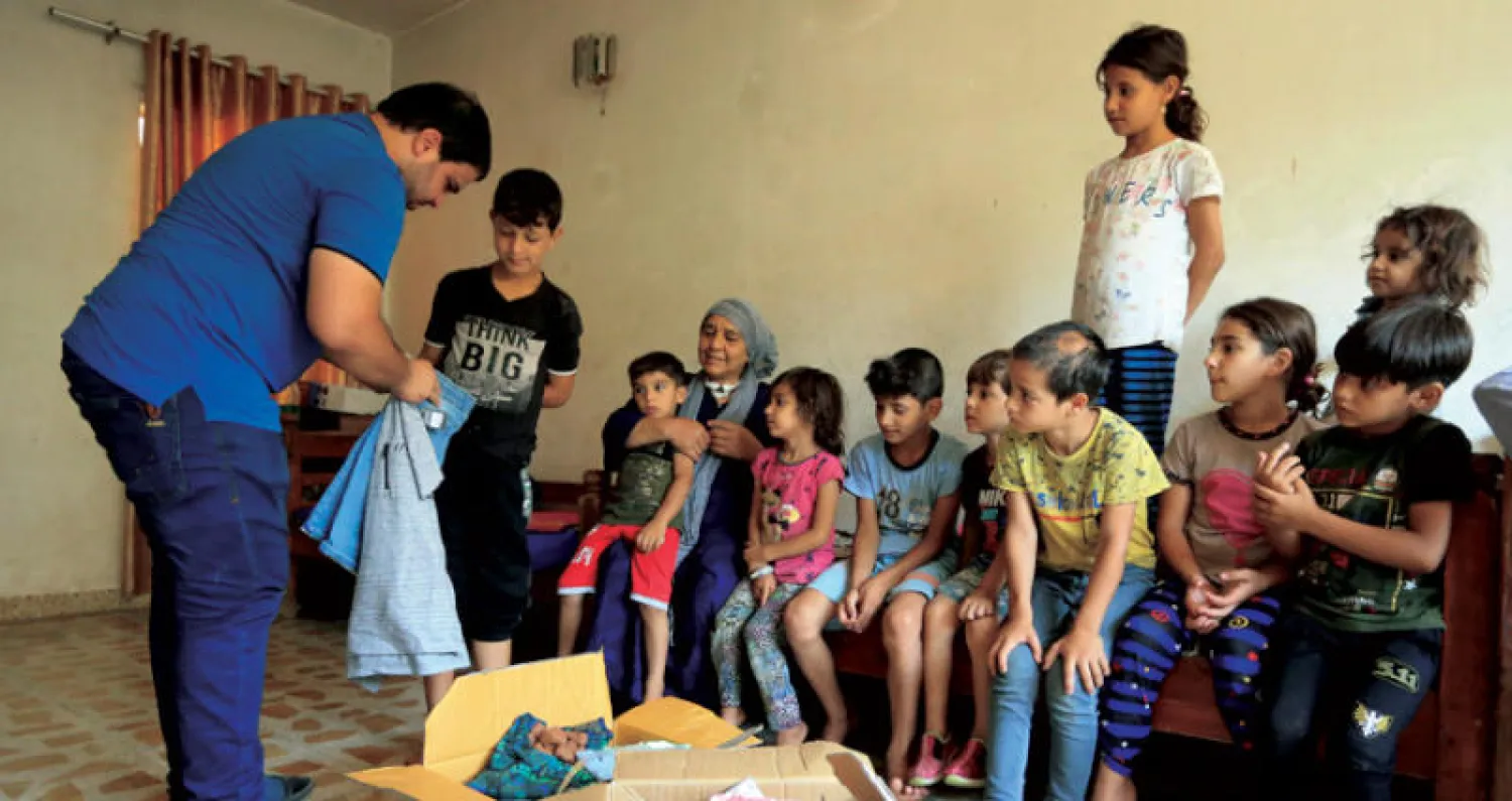 عراقية فقدت خمسة أبناء على يد {داعش} مع أحفادها تتلقى مساعدات في الموصل (رويترز)