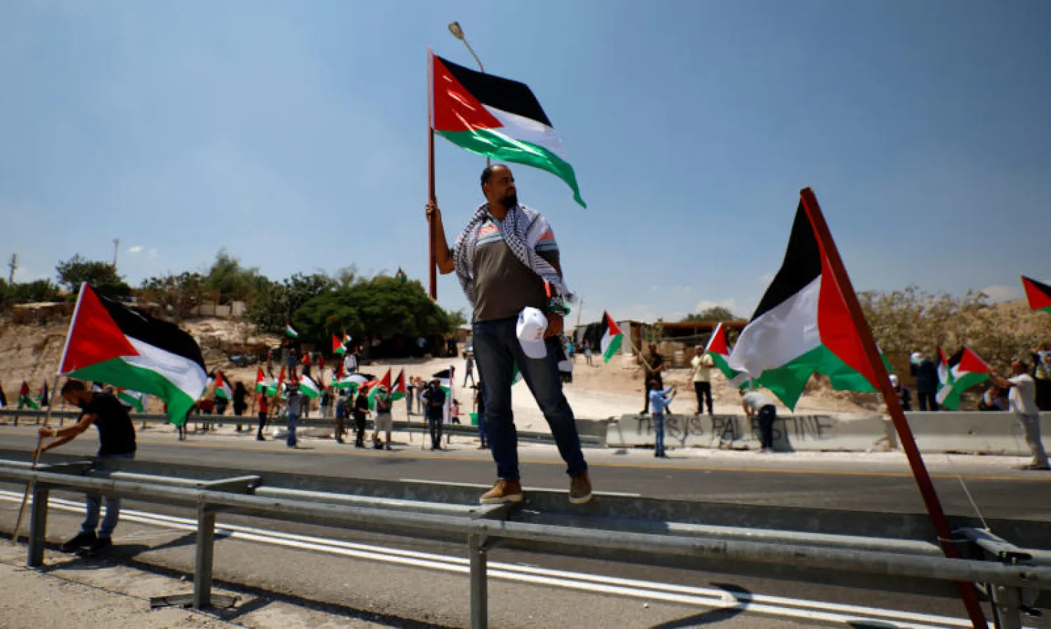 متظاهرون يحملون الأعلام الفلسطينية (رويترز)