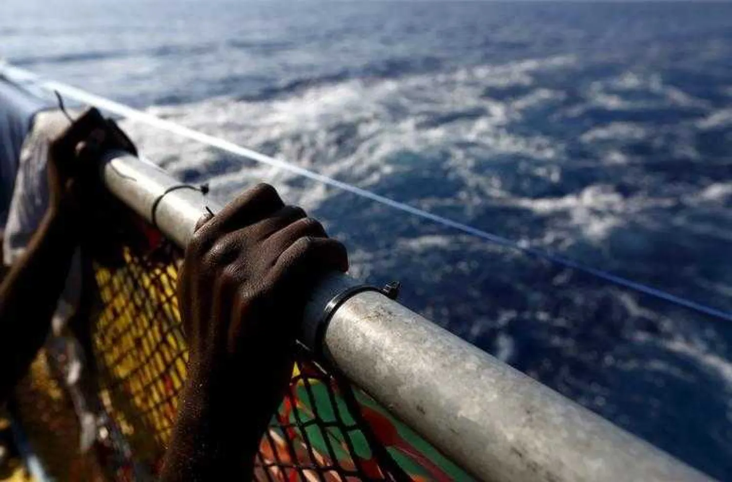 A migrant holds onto a railing at the stern of the Medecins Sans Frontiere (MSF) rescue ship Bourbon Argos somewhere between Libya and Sicily August 8, 2015. REUTERS/Darrin Zammit Lupi