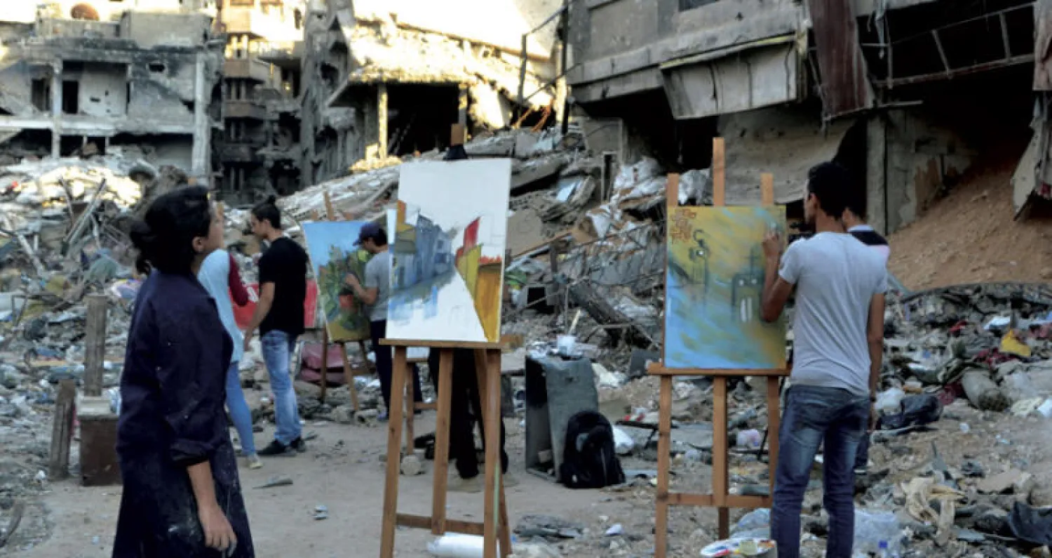 فنانون يرسمون وسط الدمار في مخيم اليرموك (أ.ف.ب)