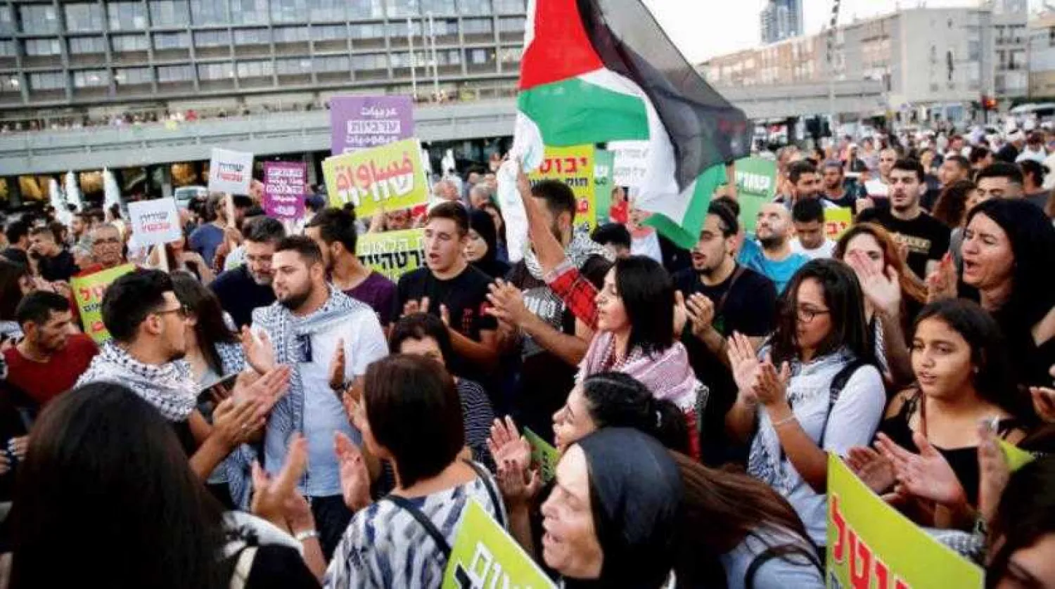 Palestinians raise their flag during a demonstration in Tel Aviv against the Nation-State Law. (AP)