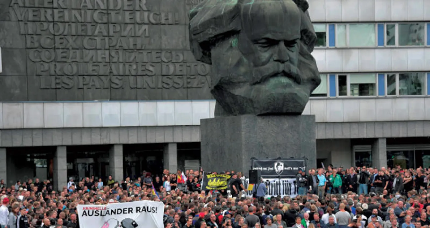 مظاهرة لليمين المتطرف في ساحة مدينة كيمنتس شرق ألمانيا ترفع يافطة كتب عليها «الأجانب مجرمون» قرب تمثال لكارل ماركس (رويترز)