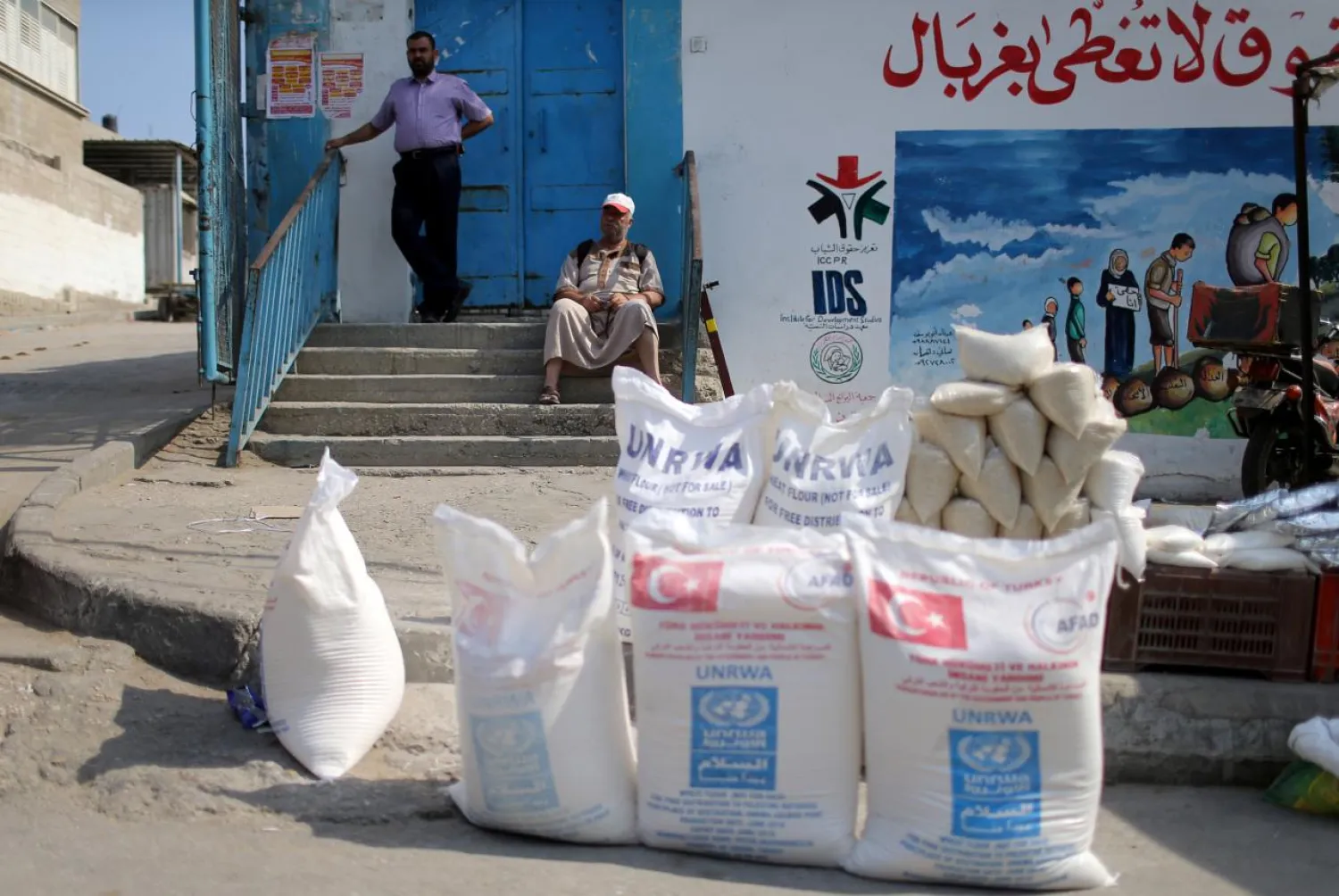 A Palestinian man sits next to food supplies at an aid distribution center run by UNRWA in Khan Younis in the southern Gaza Strip September 1, 2018. (Reuters)

