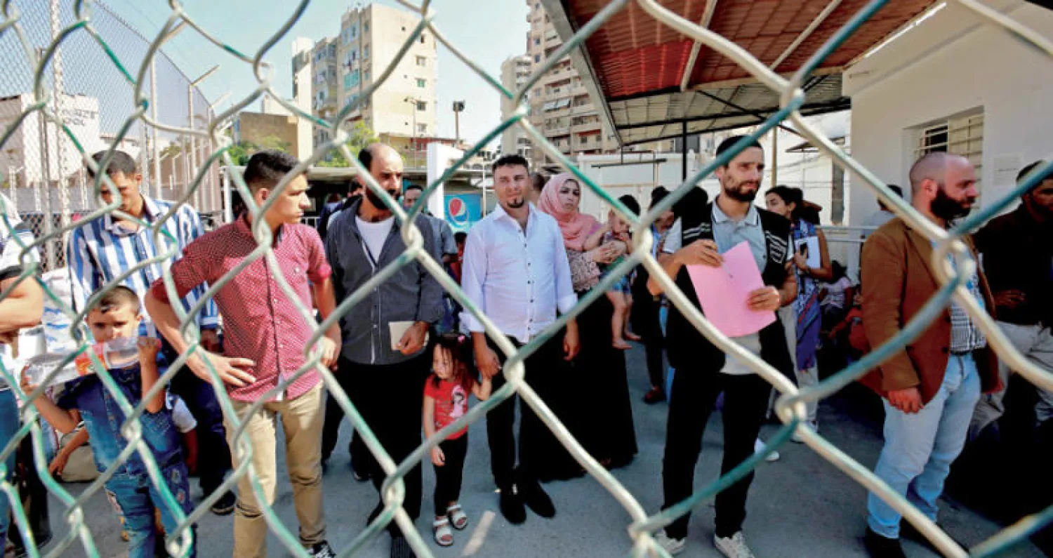 نازحون سوريون تجمعوا في مركز ببيروت أمس استعداداً لعودتهم إلى سوريا عبر حافلات (أ.ف.ب)