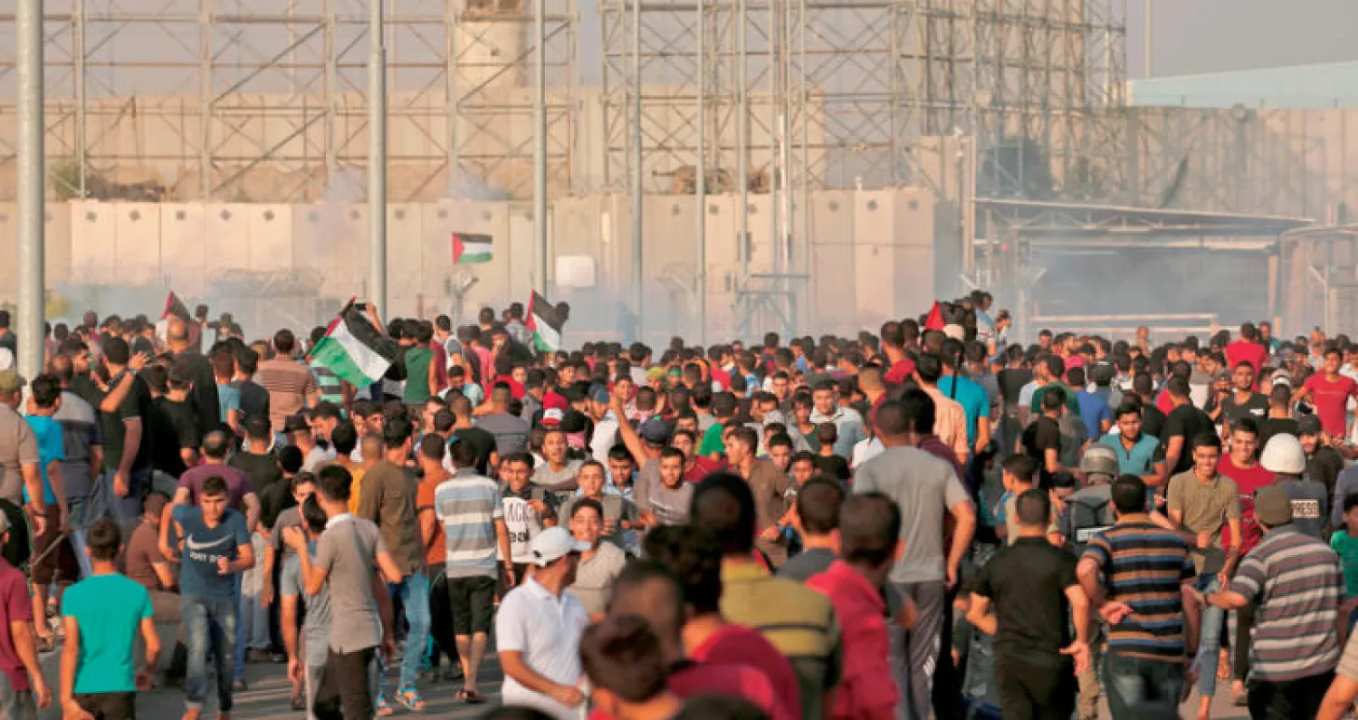 فلسطينيون يلوحون بالأعلام خلال مظاهرات احتجاجية قرب معبر بيت حانون (إيرز) شمال غزة أمس (أ.ف.ب)