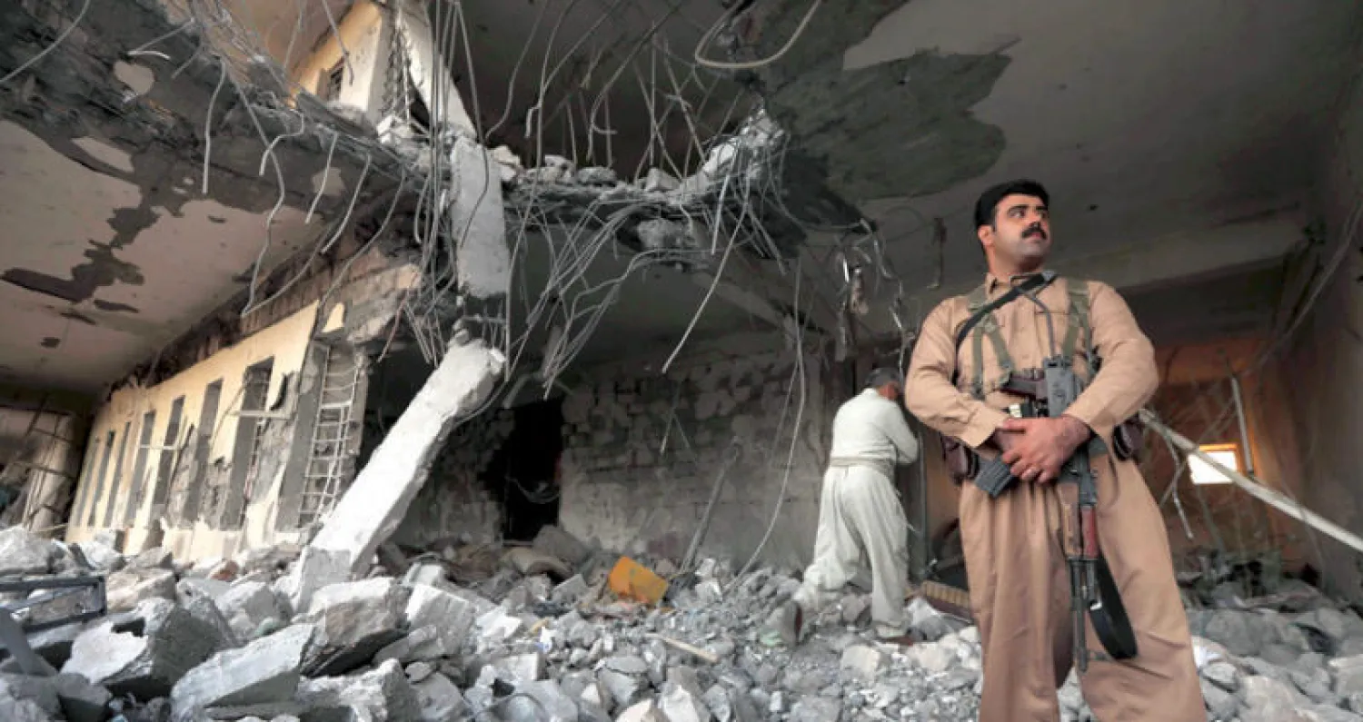 عناصر من الحزب الديمقراطي الكردستاني يتفقدون الدمار بمقرهم بعد هجوم صاروخي في كويسنجق أمس (أ.ف.ب)