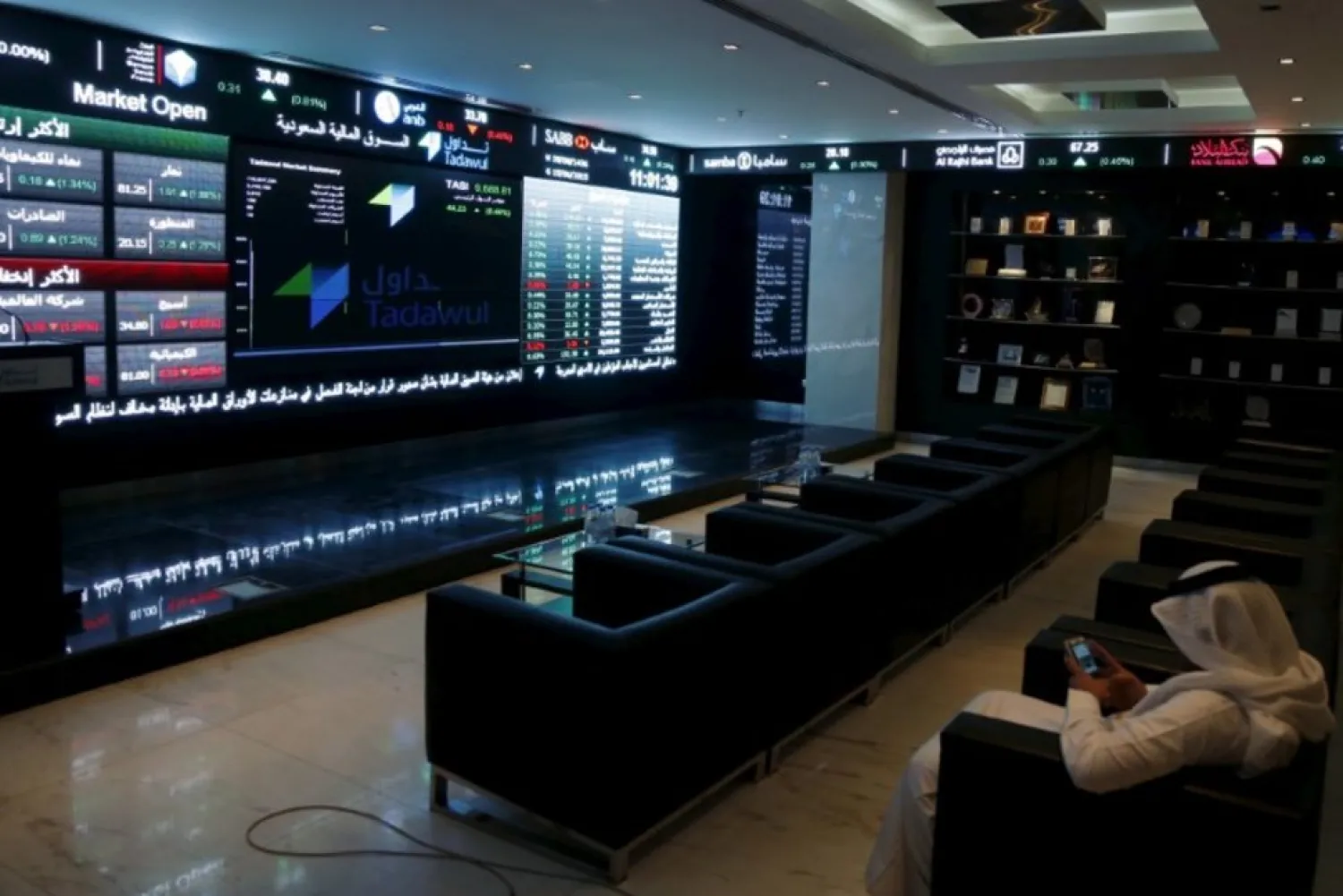 A trader uses his mobile as he monitors screens displaying stock information at the Saudi Stock Exchange (Tadawul) in Riyadh June 15, 2015. REUTERS/Faisal Al Nasser/File Photo Reuters