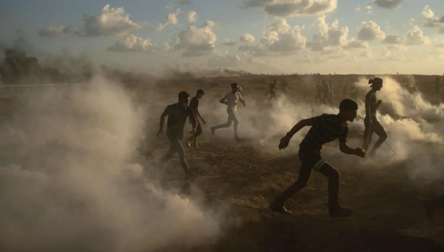 فلسطينيون يهربون من قنابل الغاز المسيل للدموع في مسيرة العودة- أرشيفية (أ.ب)