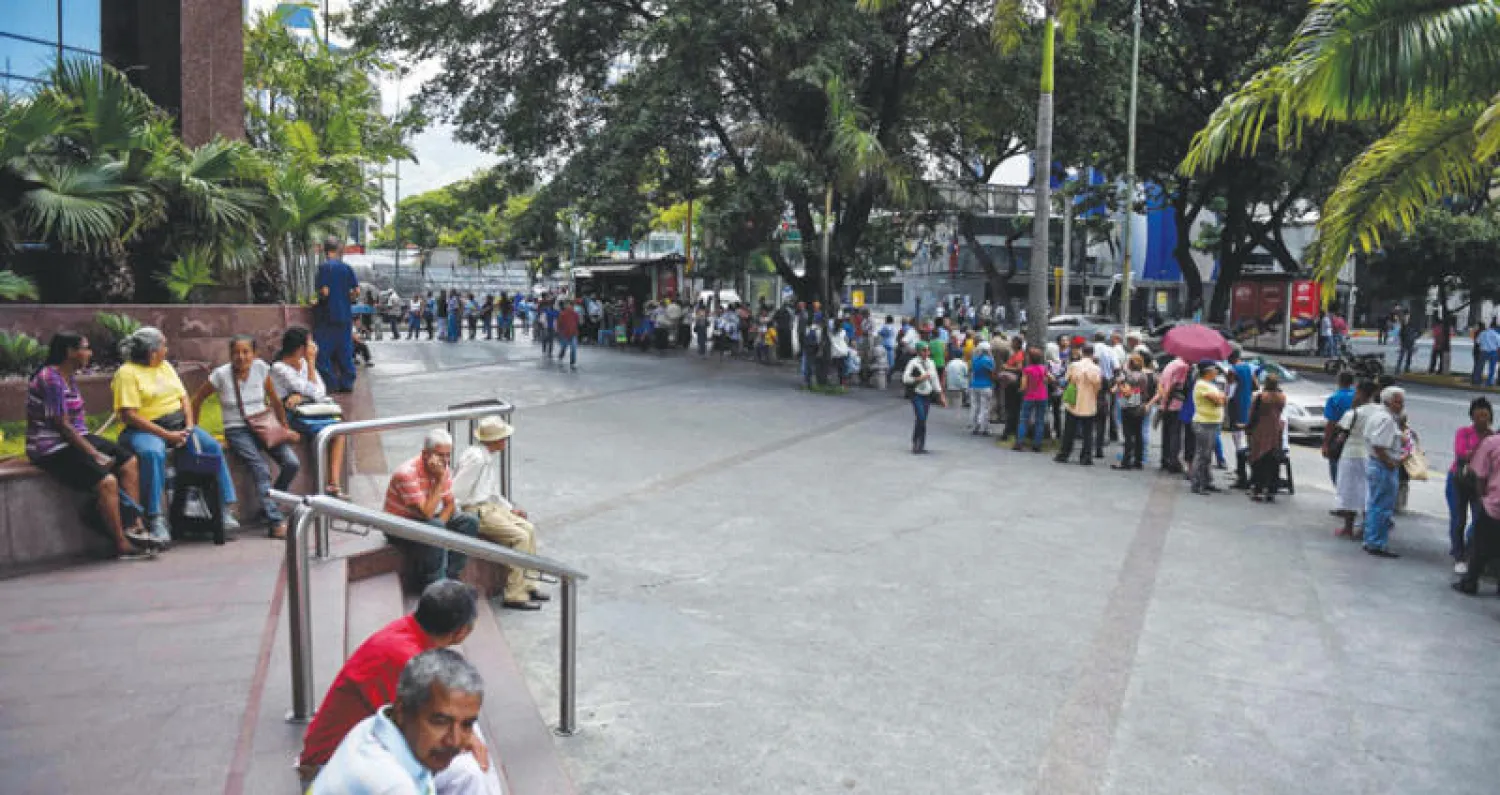 اصطفاف المتقاعدين لساعات خارج البنوك في فنزويلا لسحب النقود (أ.ف.ب)