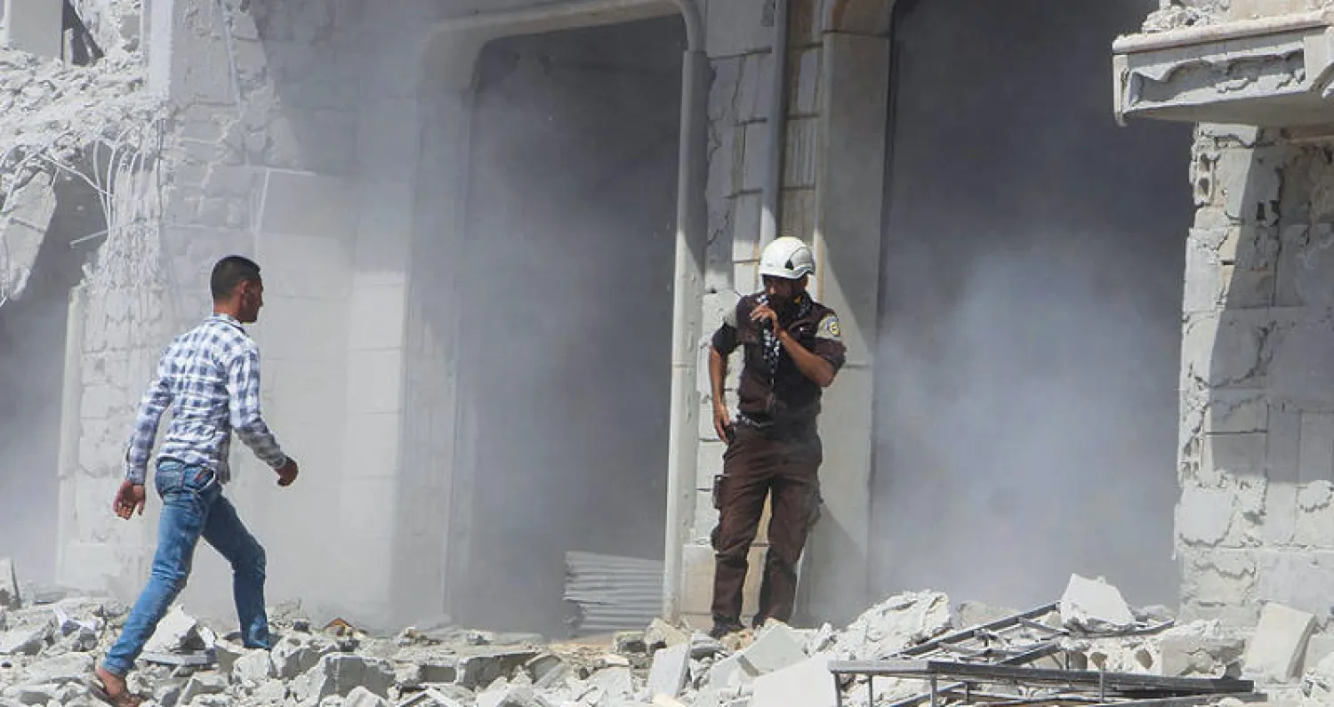 أحد عناصر الدفاع المدني (الخوذ البيضاء) يتحدث في اللاسلكي أمام مبنى تعرض للدمار بعد قصف جوي في «الهبيط» قرب إدلب أمس (أ.ب)