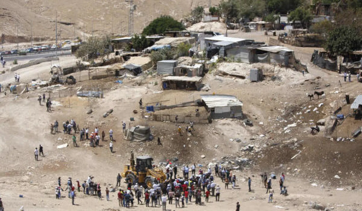 فلسطينيون يقفون حول جرافة في قرية خان الأحمر بالضفة الغربية المحتلة (آ.ب)