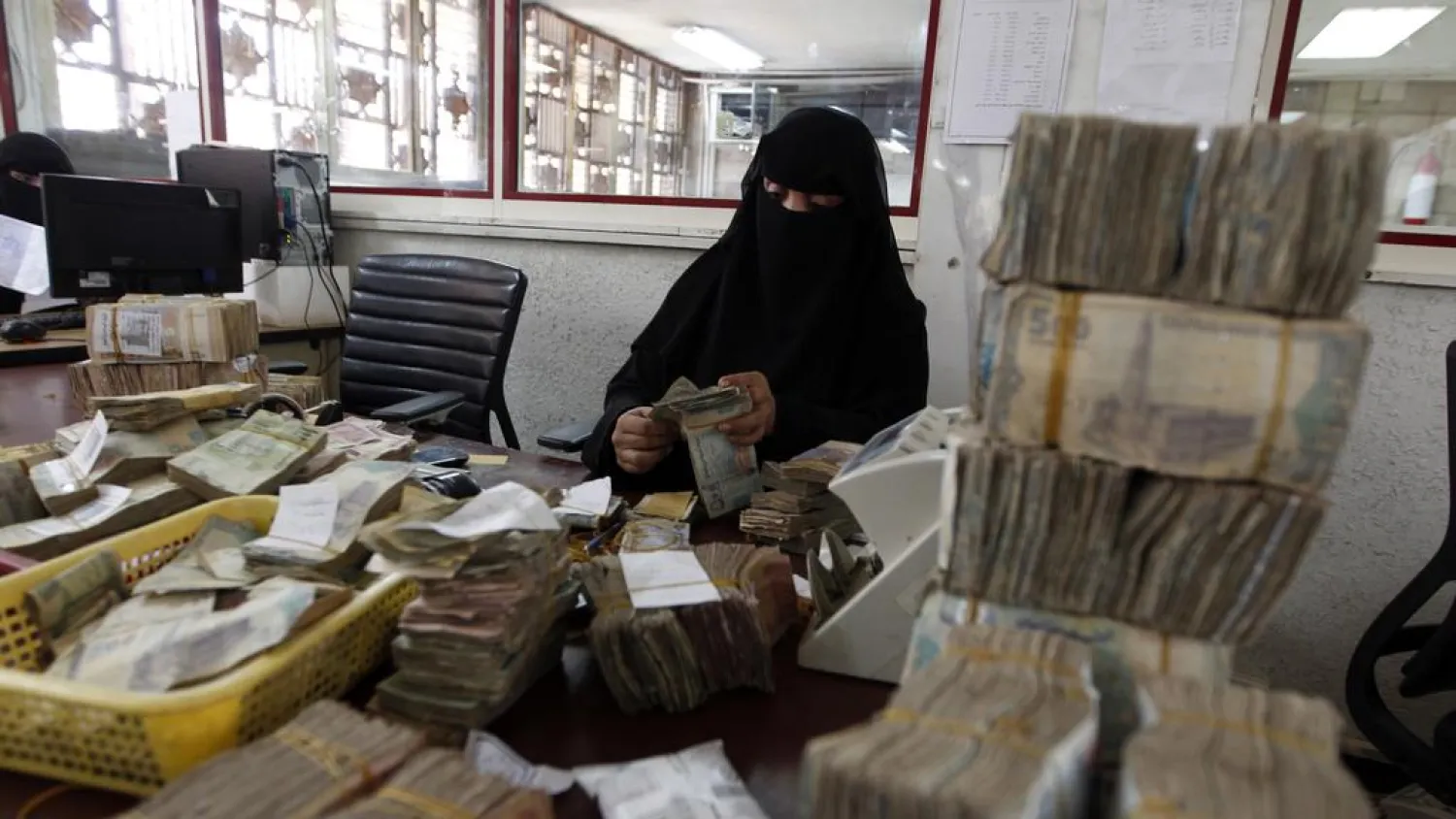 An employee counts stacks of Yemeni currency at Yemen's central bank in Sanaa. (AFP)