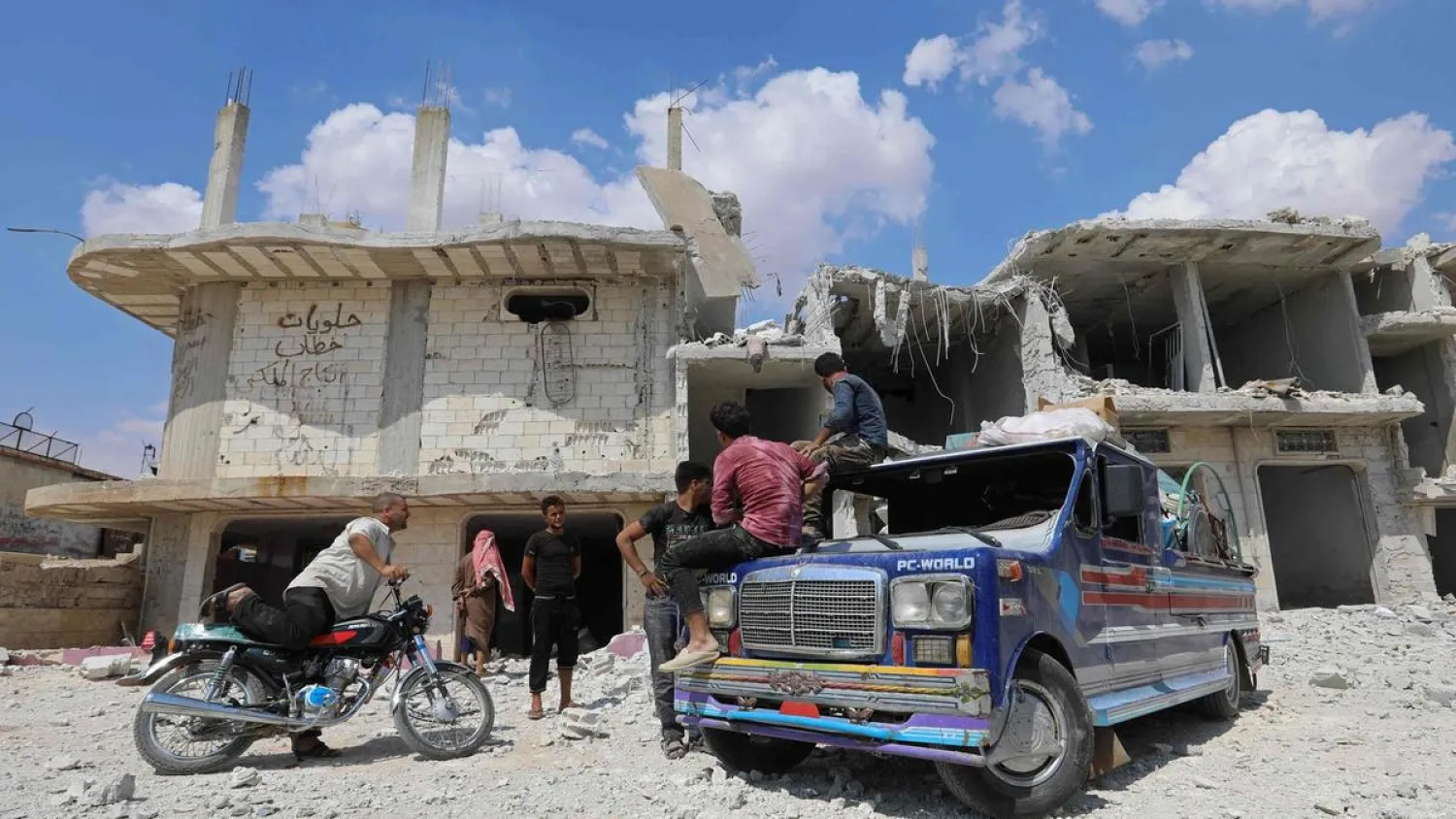 Syrian men load a pick up truck close to the destroyed buildings after regime attacks on the town of al-Habeet on the southern edges of Idlib. (AFP)