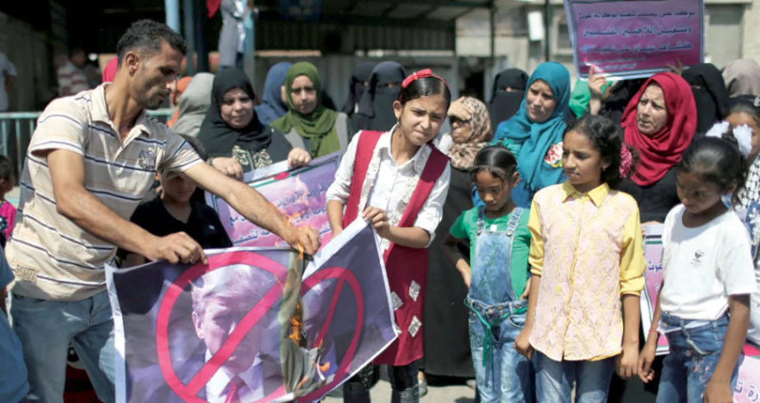 فلسطينيون يحرقون صورة ترمب احتجاجاً على وقف تمويل {أونروا}  (رويترز)