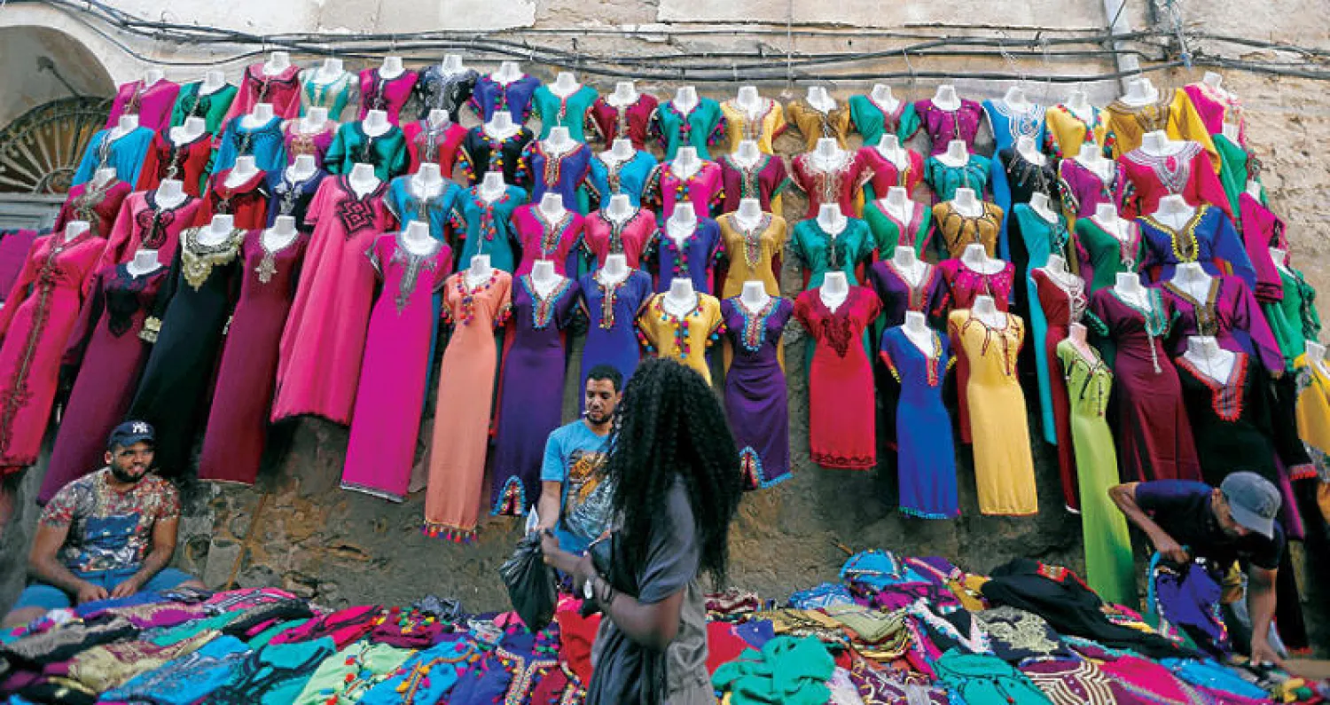 بائع تونسي يعرض مجموعة من الثياب النسائية التقليدية في سوسة (رويترز)