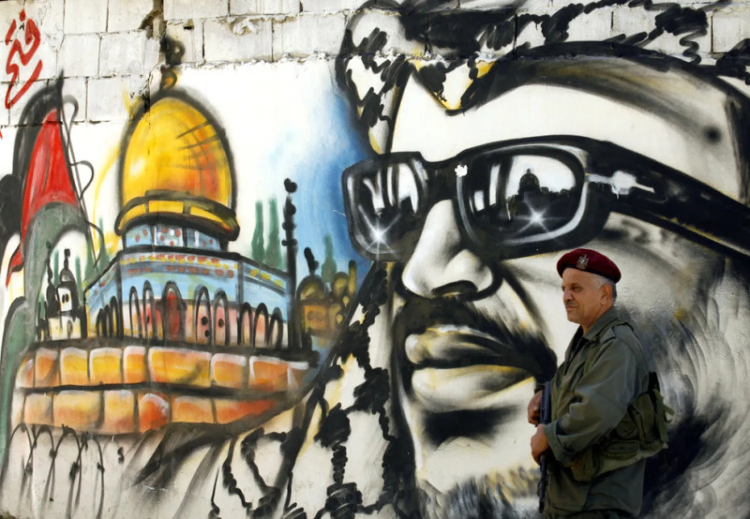 A Palestinian security officer stands by a mural of Yasser Arafat. (AFP)