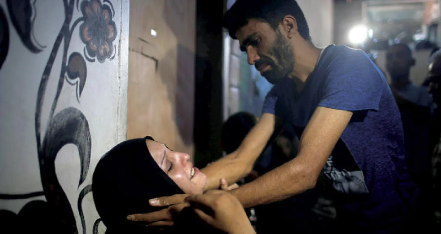 يواسي والدة الفتى شادي عبد العال الذي قتلته قوات الاحتلال الإسرائيلي أول من أول الجمعة على حدود قطاع غزة (رويترز)