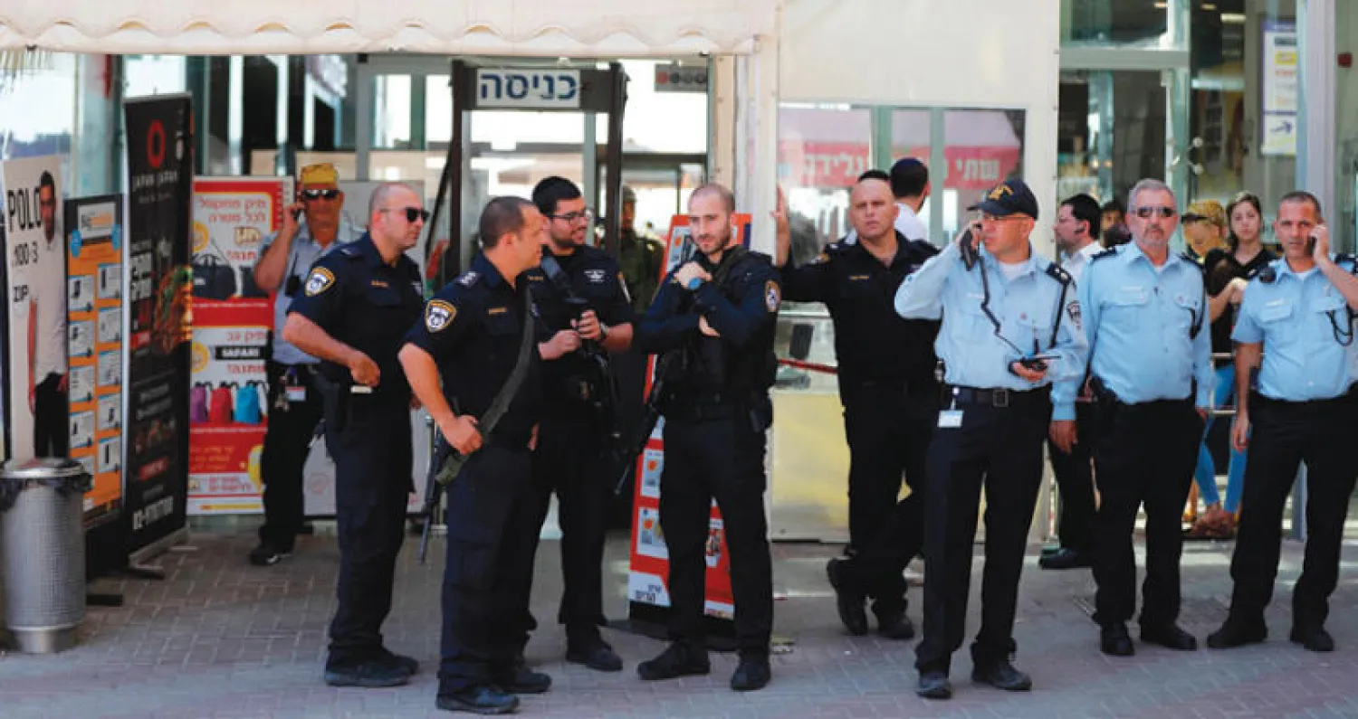 قوات من الأمن والشرطة الإسرائيليين في موقع الطعن أمام متجر في مستوطنة غوش عتصيون (أ.ف.ب)