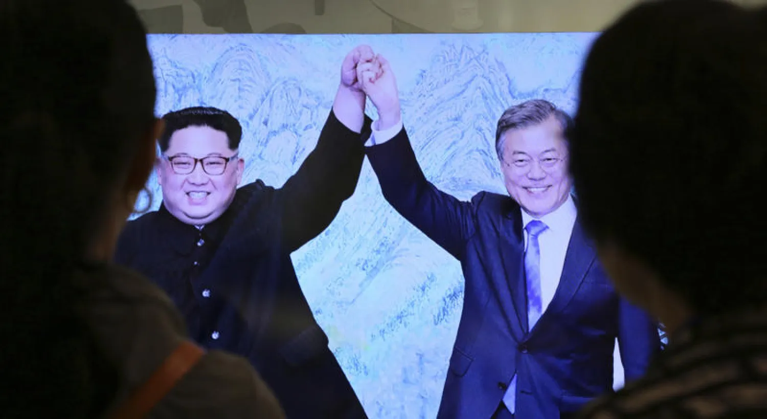 كوريون يشاهدون شاشة تعرض صورة من القمة المنعقدة في 27 أبريل (نيسان) الماضي بين الزعيمين الكوريين (أ.ب)