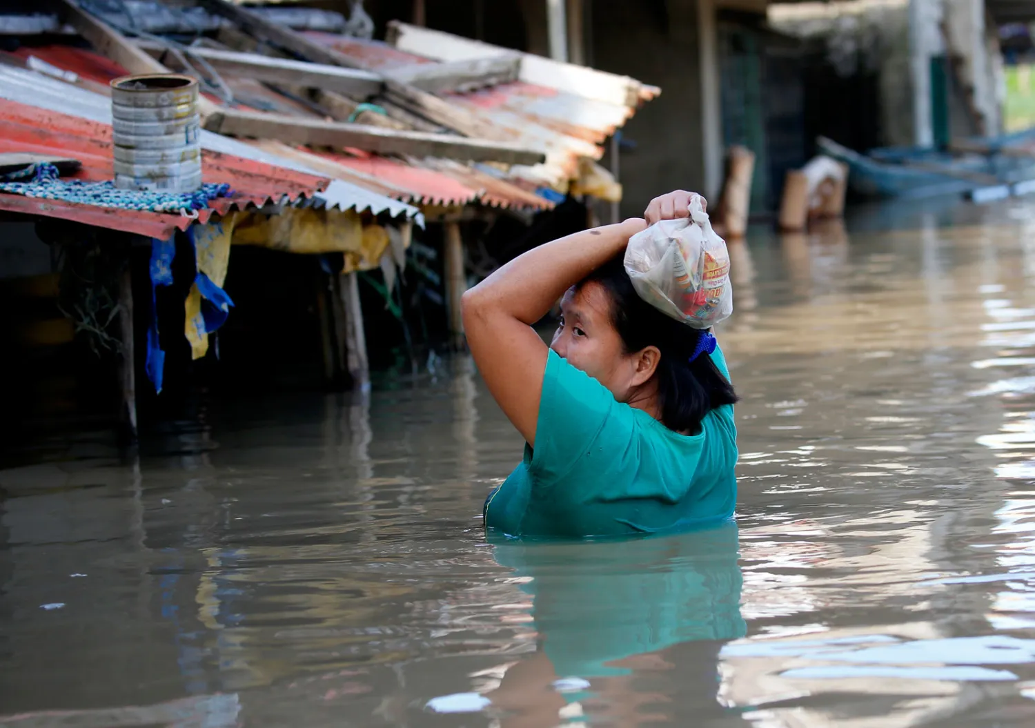  سيدة فلبينية تحاول توصيل الطعام لعائلتها وسط الفيضانات (أ.ب)