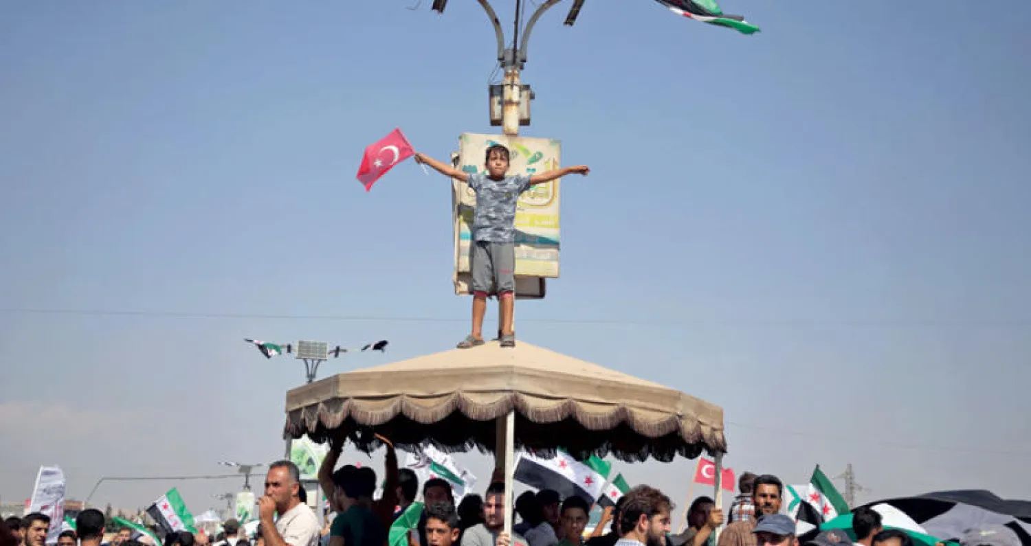 فتى يحمل علم تركيا خلال مظاهرات في ريف إدلب أمس (أ.ف.ب)