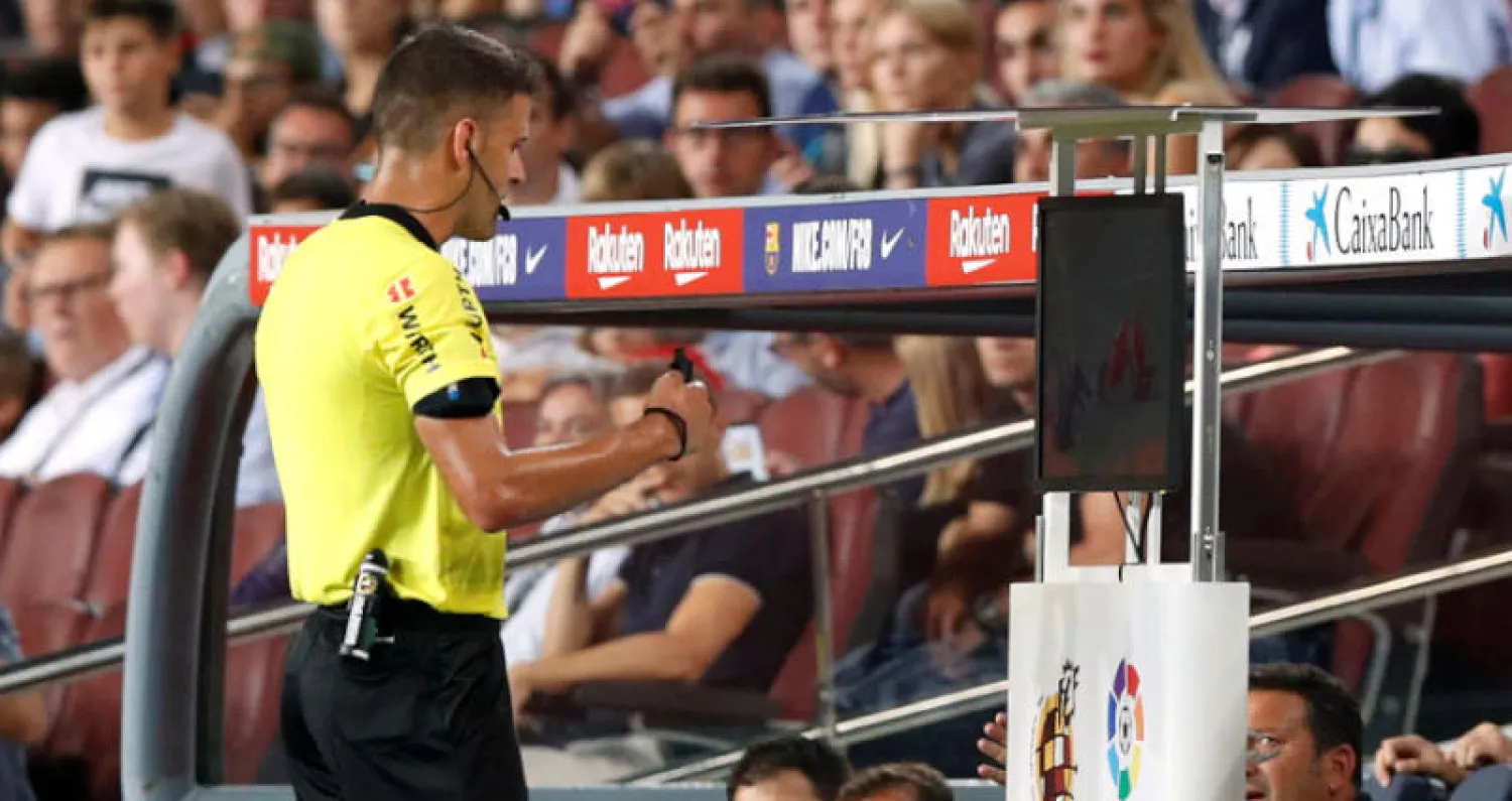 الحكم مانزانو يراجع الفيديو قبل طرد لانغليه لاعب برشلونة (رويترز)