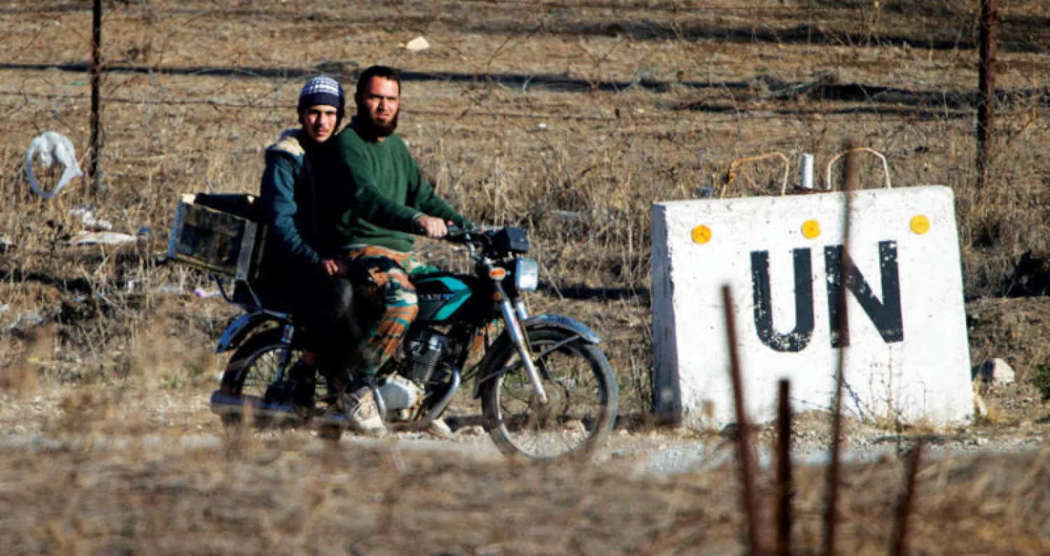 صورة أرشيفية لعنصرين معارضين قرب لافتة للأمم المتحدة قرب الجولان (أ.ب)