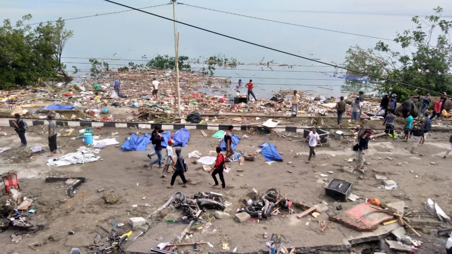 People walk past dead bodies a day after an earthquake and a tsunami hit Palu, on Sulawesi island on September 29, 2018. (AFP)