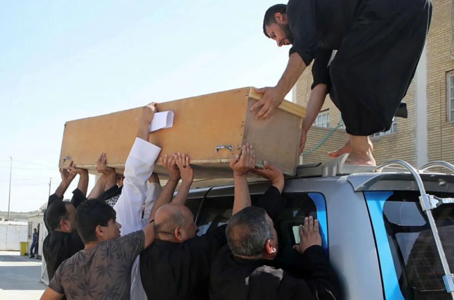 Family members of slain activist Soad al-Ali load her coffin onto a vehicle before burial, in the Iraqi city of Basra, on September 26. (AP)