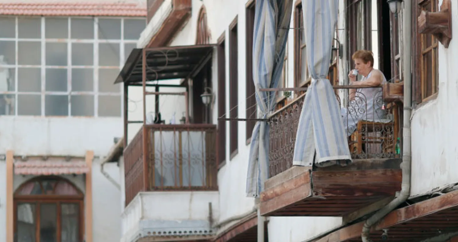 سورية ترتشف قهوتها على شرفة منزلها في حي باب شرقي في دمشق القديمة أول من أمس (أ.ب)