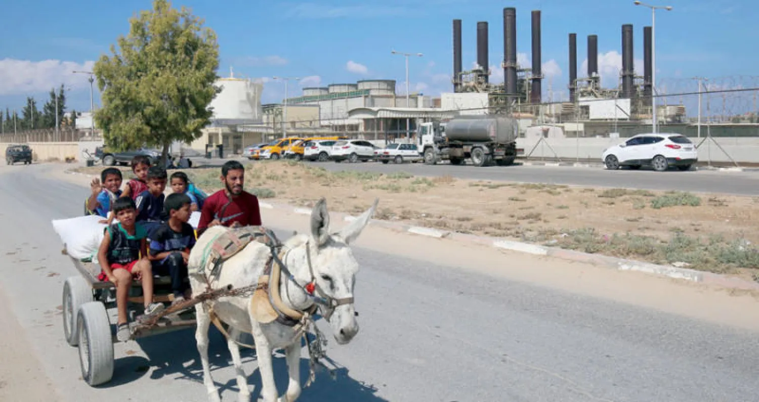 عربة يجرها حمار تنقل مواطنين تمر أمام محطة الوقود المركزية في غزة حيث دخلت أولى شاحنات الوقود (أ.ف.ب)